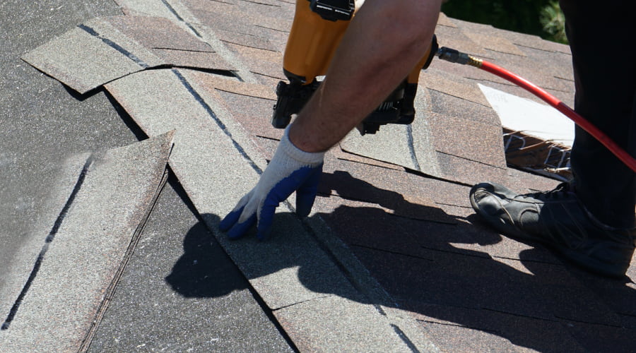 close up of a roofer using a tool to install new shingles during roofing repair service floyd county ga